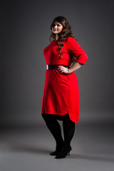 Plus size fashion model in red dress, fat woman on gray background, overweight female body