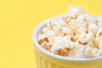 Fresh pop corn. Bright yellow background. Small white bowl