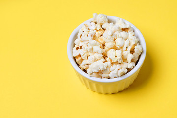 Fresh pop corn. Small white bowl. Bright yellow background