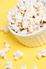 Fresh pop corn. White plate. Yellow background
