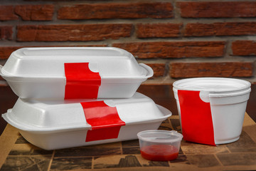 Breakfast, snack, lunch, brunch, dinner with home delivery in containers. A set of products. Composition. White plastic containers with a red label, in the background a brick wall