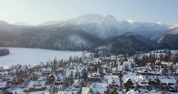 aerial view of a small snowy town and mountains in winter