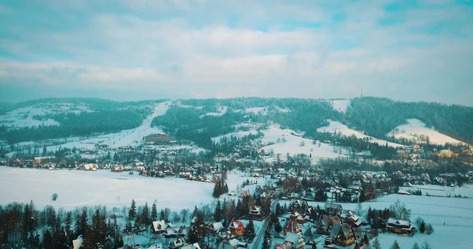 aerial view of a small snowy town and mountains in winter