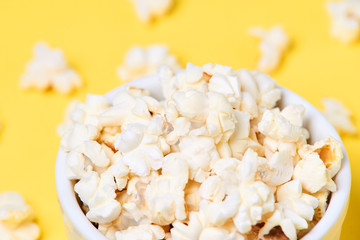 White plate. Fresh pop corn. Yellow background