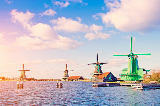 Spectacular view of the water and windmills in Zaanse Schans, Holland, Europe against the backdrop of a cloudy sky at sunset.