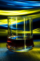A glass of cognac on the table in night club with bokeh effect.