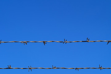 Double barbed wire fence against clear blue sky with copy space