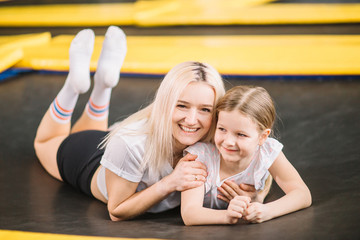 mother and little daughter playing at playground and lying on trampoline