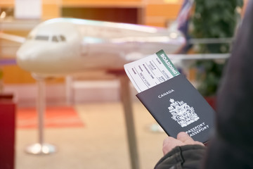 A man with a Canadian passport and boarding pass looks departure