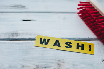 Cleaning house or office concept. Red cleaning brush and WASH inscription on a white wooden...