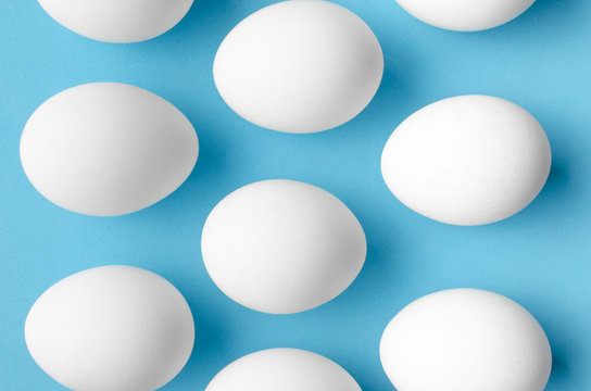 White chicken eggs on blue background.