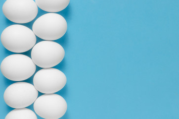 White chicken eggs on blue background.
