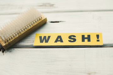 Cleaning house or office concept. Wooden cleaning brush and WASH inscription on a white wooden...