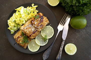 Fried fish with salad on a gray plate.