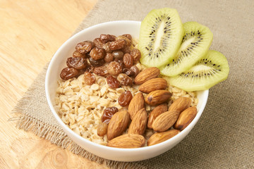 Neutral background. Oatmeal with kiwi raisins and almonds
