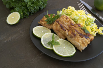 Fried fish with salad on a gray plate.