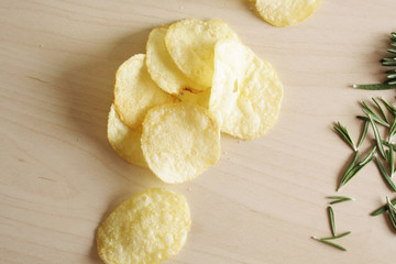 potato chips on a wooden background of rosemary