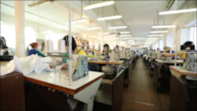 Industrial size textile factory, workers on the production line, sewing production, women work for sewing machines, sewing workshop, blur, unrecognizable