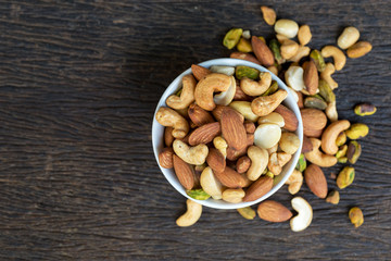 Healthy food and snack : mixed nuts in white ceramic bowl from above,  Walnut, pistachios, almonds, hazelnuts and cashews..