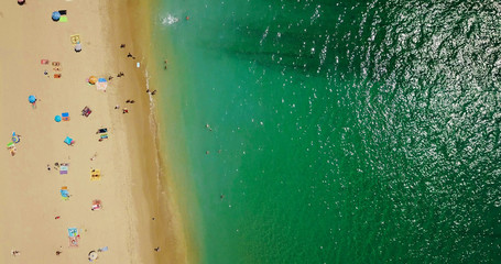 Fototapeta na wymiar Aerial View From Flying Drone Of People Crowd Relaxing On Beach In Portugal