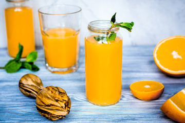 healthy orange cocktail with mint leaves in bottle on kitchen ba