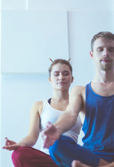 Young healthy couple in yoga position on white background