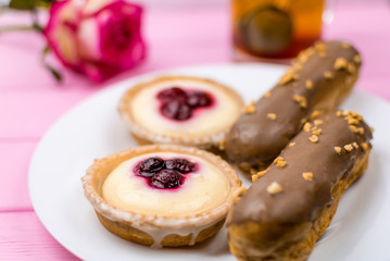 Different cakes with custard and cream and berries on a white plate.