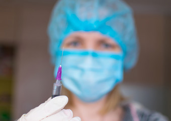 A nurse holds an elongated hand with a syringe.