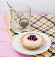 Cake and tea in a glass on a pink wooden background.