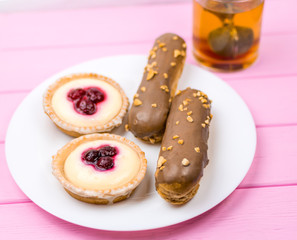 Different cakes with custard and cream and berries on a white plate.