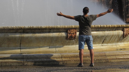 Fototapeta na wymiar Rinfrescarsi alla fontana - turista in estate 