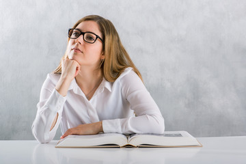 Business Frau mit dickem Buch sitzend am Tisch, denkt nach