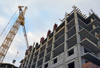 Fototapeta na wymiar Building crane and building under construction, cloudy sky