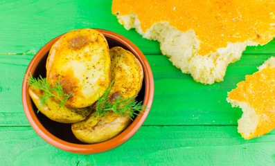 Baked potatoes in a plate on a green wooden background.