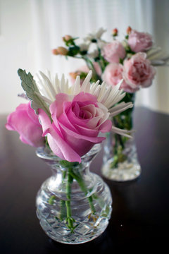 Two Crystal Vases Filled With Roses And Other Small Flowers