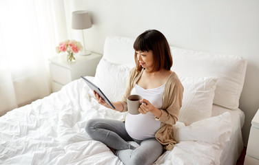Obraz na płótnie Canvas happy pregnant asian woman with tablet pc at home