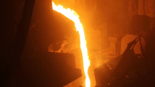 Plant for the production of steel. An electric melting furnace. Factory worker takes a sample for metal.