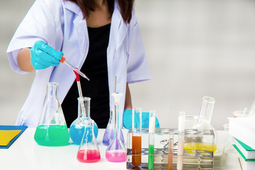 The chemist in protective eyeglasses working by test tube with reagent in lab,she is wear blue rubber glove for protect hand when touch science tube,Scientific experiment