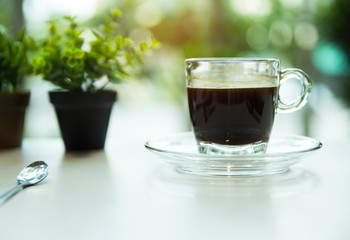 The black coffee cup put on table and coffee shopmwram light tone ,blurry light background.