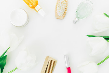 Frame with perfume, cosmetics, combs and tulips flowers on white background. Beauty blogger composition. Flat lay, top view