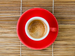 cup of espresso, viewed from above, red cup, straw table, detail