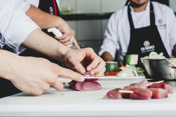 hands cutting meat inside a kitchen