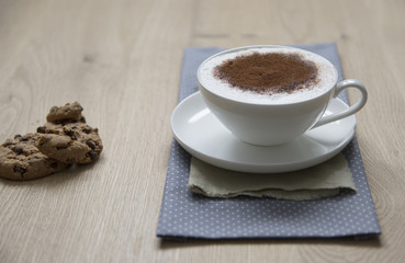 Tasse Cappuccino mit Kakao auf Holzplatte, Cookies  mit verschwommene Hintergrund