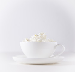 Obraz na płótnie Canvas Cappuccino Tasse mit Schlagsahne auf weissem Hintergrund und weisse Tisch