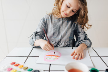 Little girl painting with paintbrush and colorful paints 