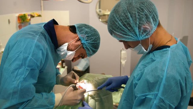 Dentist using surgical pliers to remove a decaying tooth in stomatology room