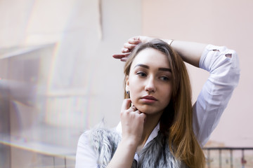 Fototapeta premium Pretty brunette model in white shirt posing in the entrance of the apartment building