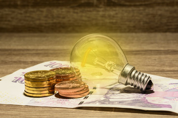 Lit European bulb placed on Czech money