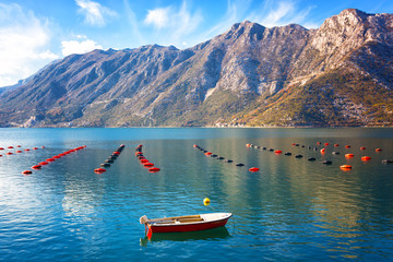 Boat and mussel farm in Boka Kotorska bay on a sunny day, Montenegro