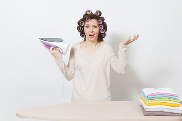 Crazy fun housewife with curlers on hair in light clothes ironing family clothing on ironing board...